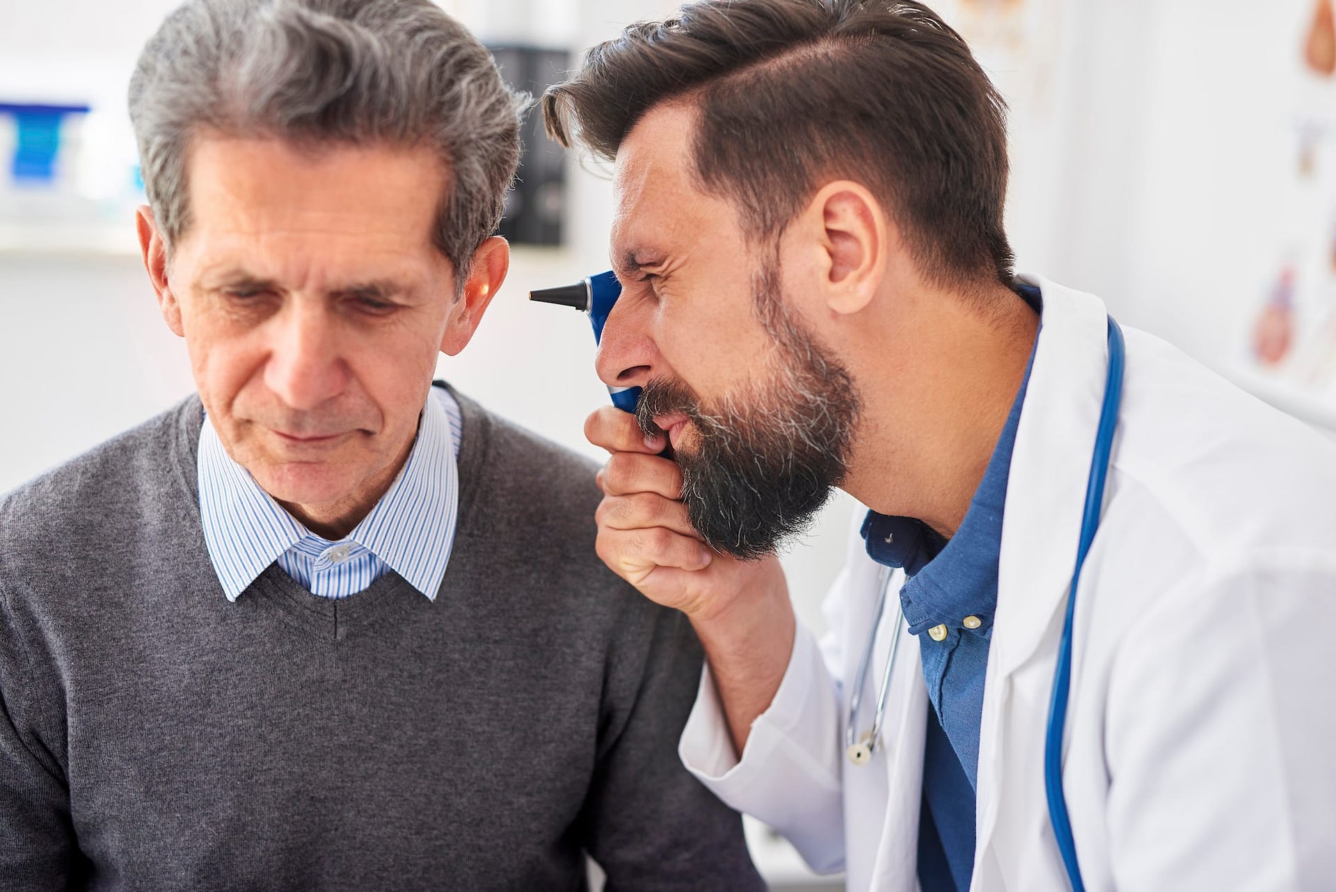 Doctor examining ear of senior man